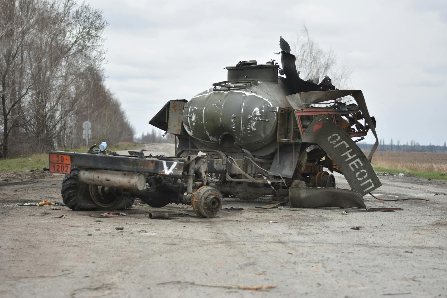 Destroyed military tank on deserted road, showcasing war impact.