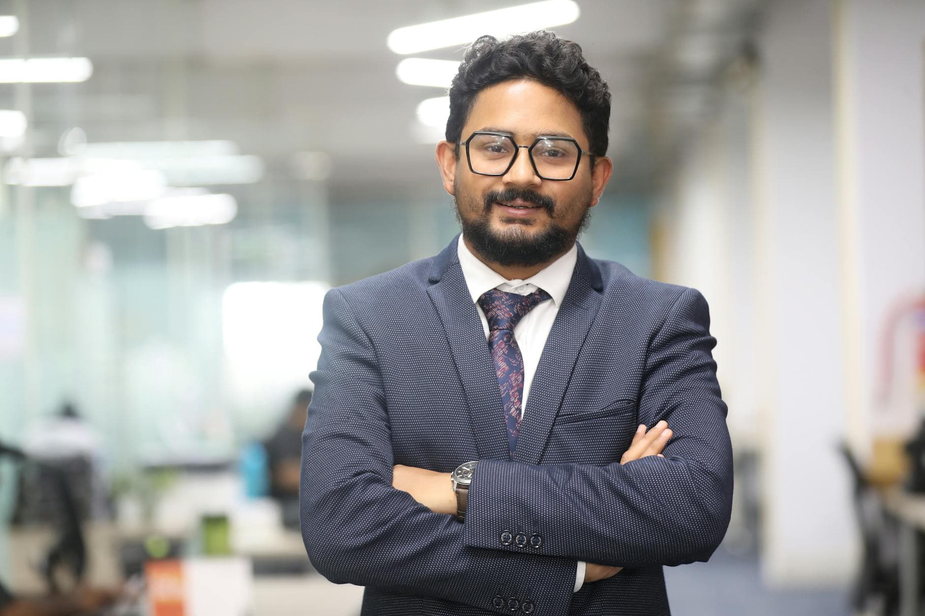 Confident man in a suit standing in a modern office, showcasing professionalism.