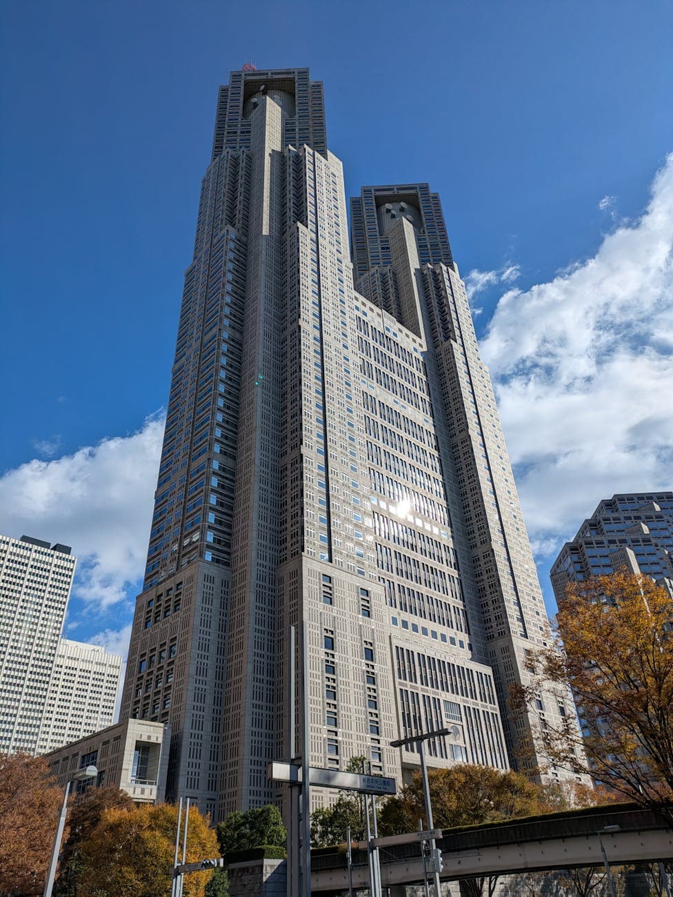 Majestic view of Tokyo Metropolitan Government Building against a bright blue sky with clouds.