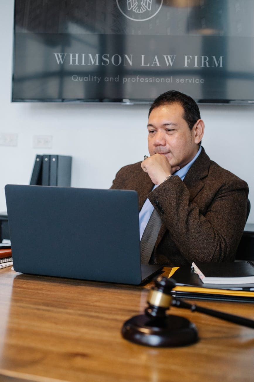 Focused lawyer working on a laptop in an office setting with legal documents.
