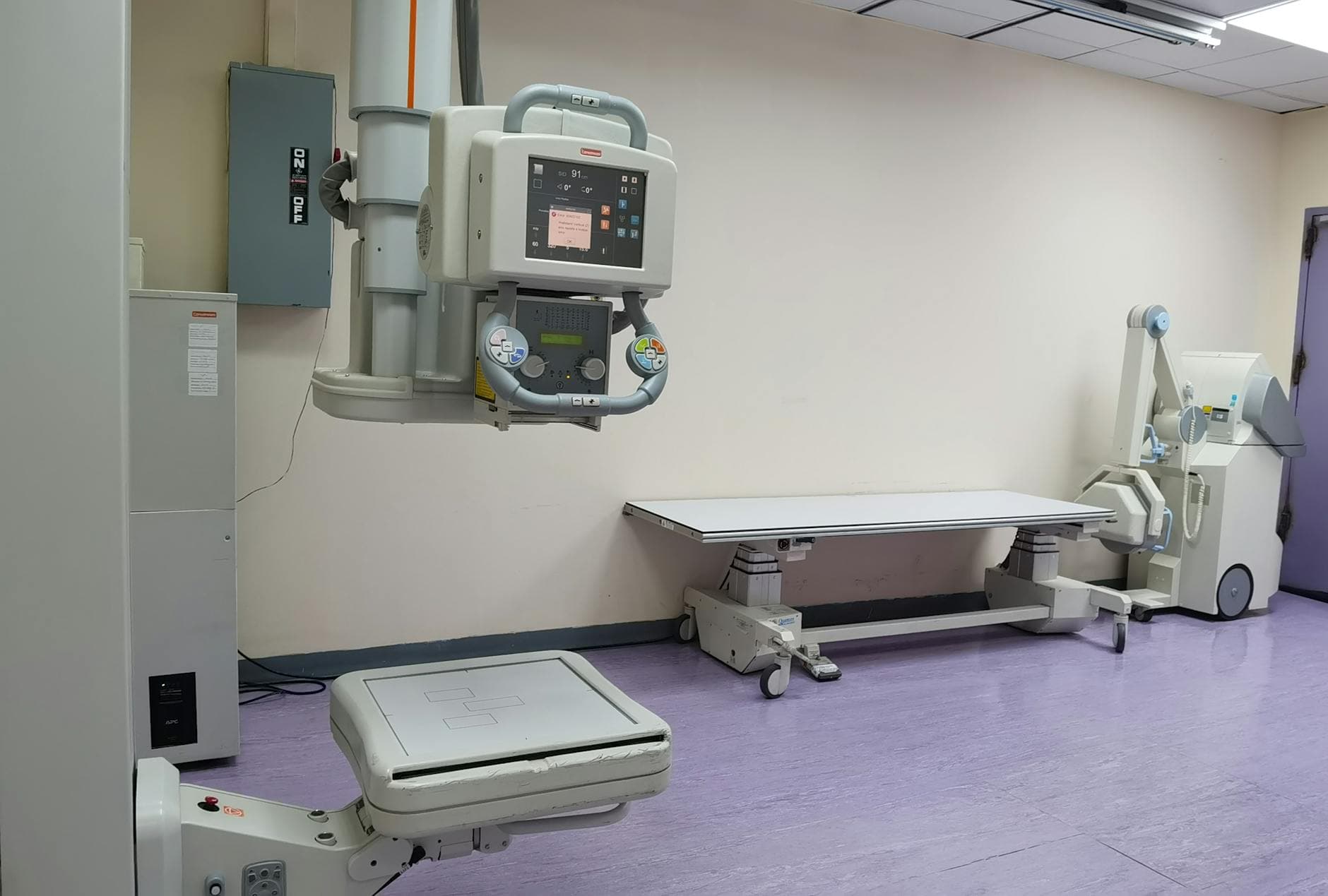 Clinical setting with X-ray machines and examination table in a healthcare facility.